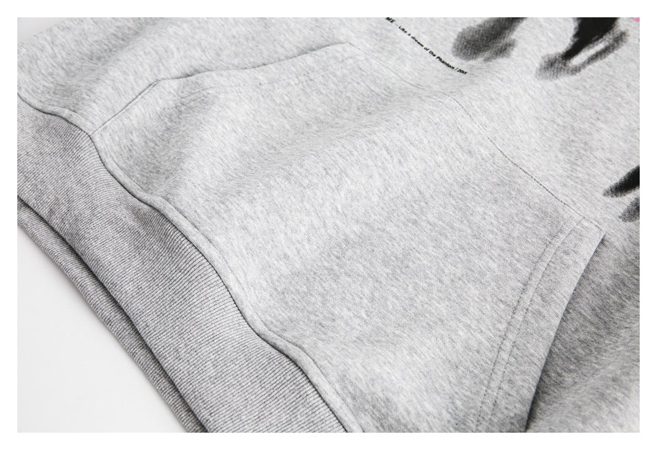 Close-up of the gray hoodie’s kangaroo pocket, ribbed hem, and part of its black chest print.