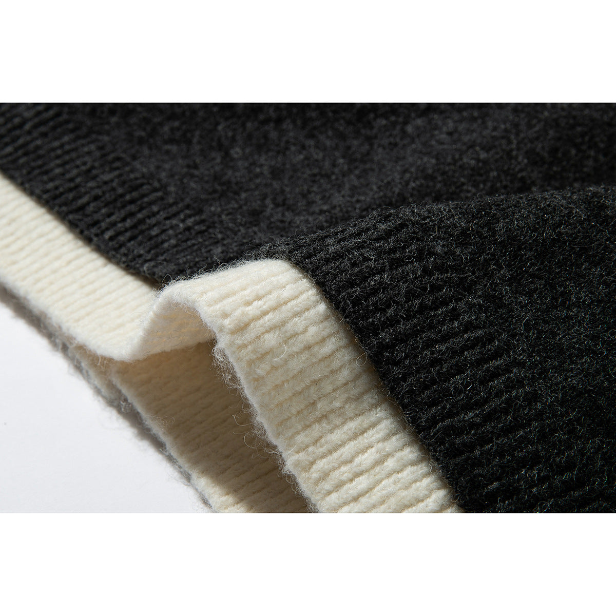 Close-up of cream ribbed trim meeting charcoal knit along a cardigan edge.