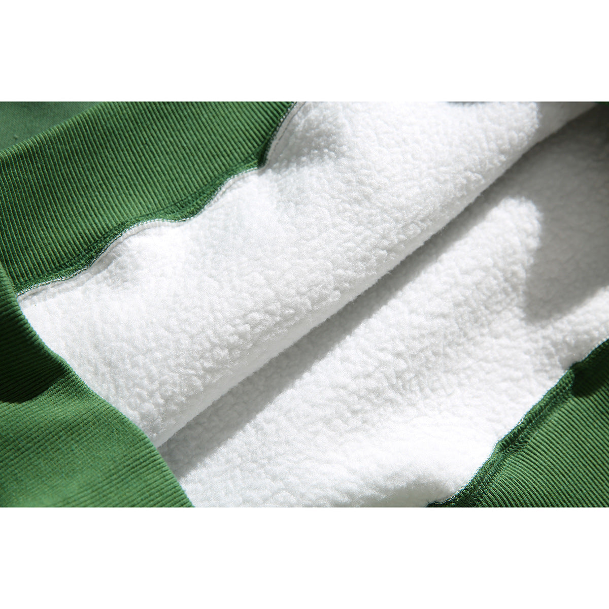 Close-up of the green hoodie’s white fluffy interior lining and ribbed green fabric edge.