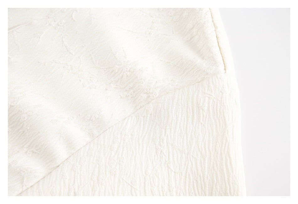 Close-up of cream textured fabric showing a seam and gathered section.