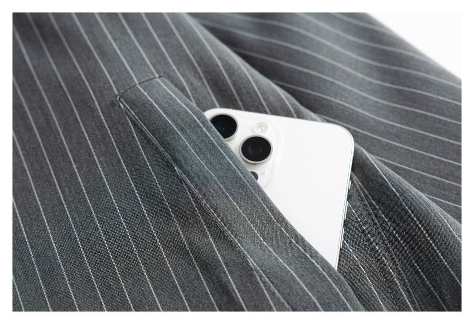 White phone tucked into the pocket of a charcoal shirt with thin light pinstripes.