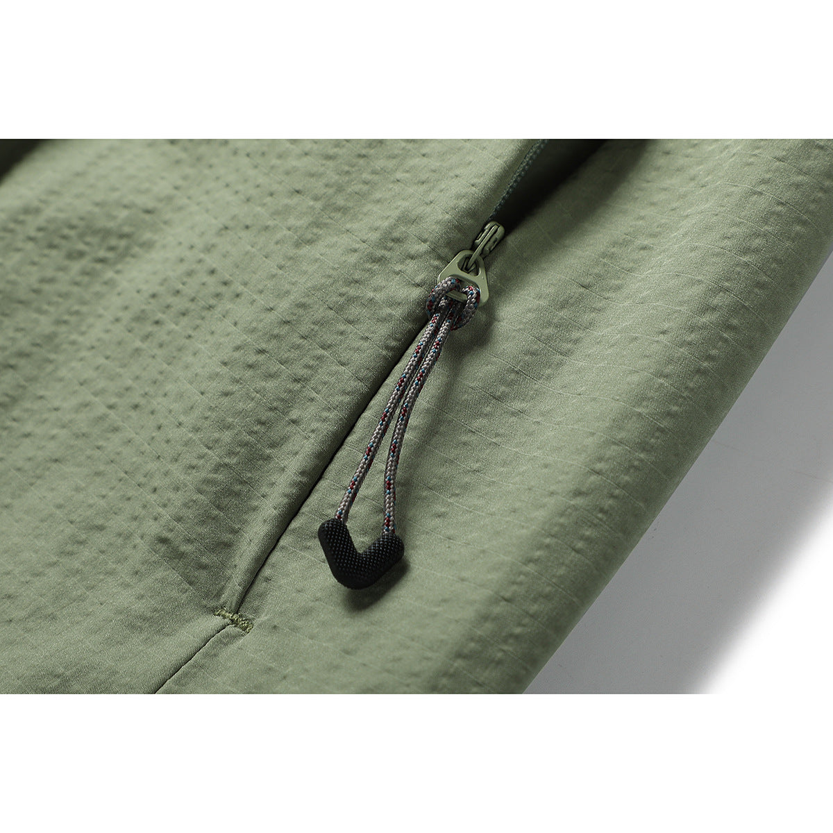 Close-up of an olive-green skirt's zipper with a braided pull cord and black grip.