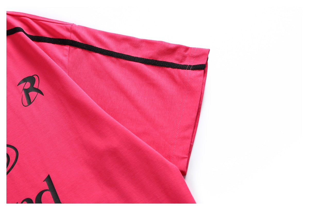 Close-up of a bright pink T-shirt sleeve with black piping and a small black emblem.