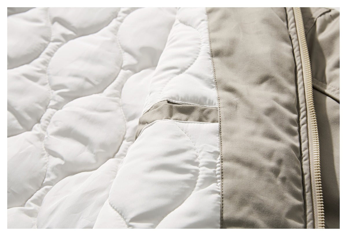 Open beige jacket detail showing white quilted lining, a pocket edge, and the zipper.