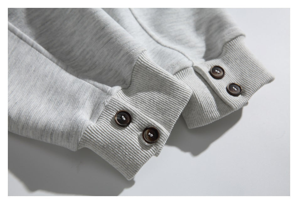 Close-up of the sweatshirt's ribbed sleeve cuffs with pairs of dark buttons.