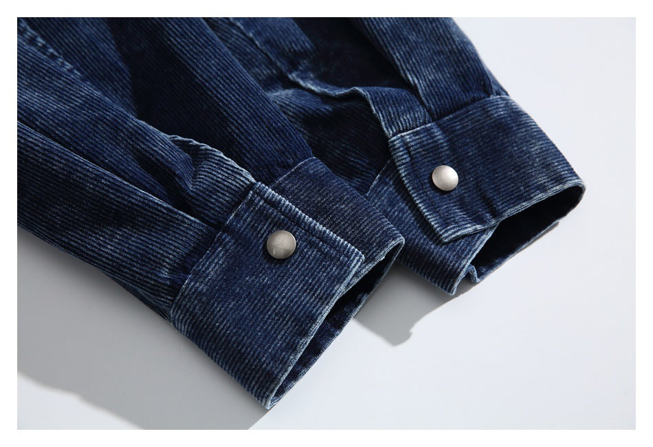 Close-up of a dark navy ribbed corduroy garment cuff with a silver snap button.