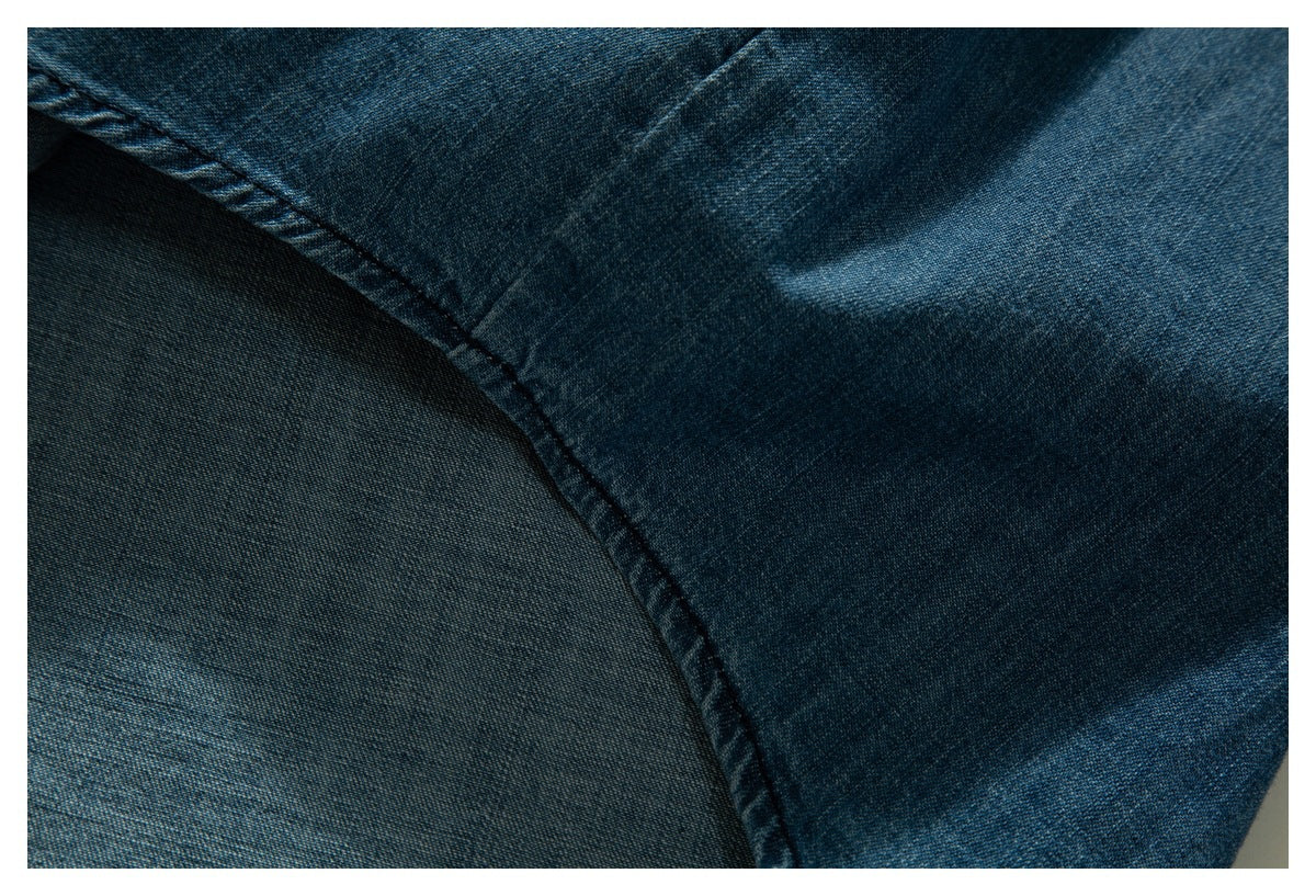 Close-up of blue denim fabric showing a curved stitched seam and the reverse side.