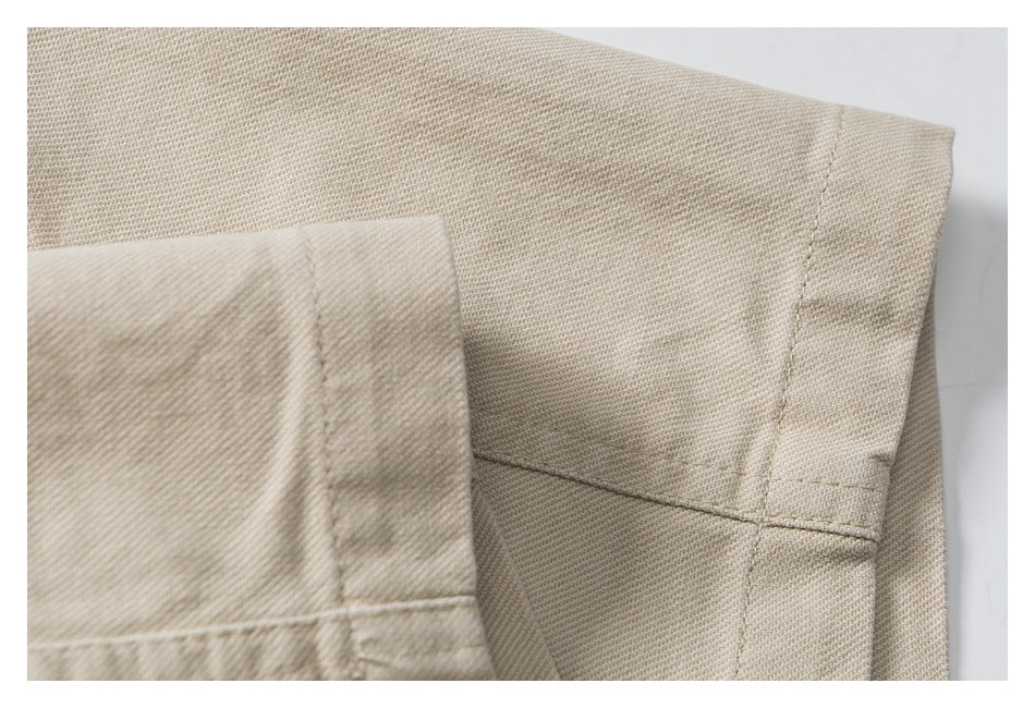 Close-up of beige trouser fabric with stitched seams and a folded edge.