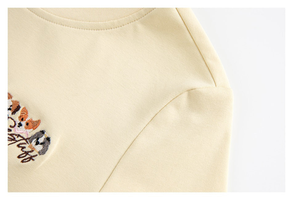 Close-up of the cream garment's shoulder and sleeve seam, with part of its cat embroidery visible.