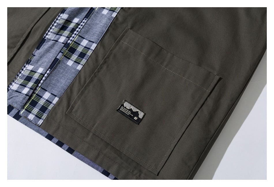 Close-up of a square olive jacket pocket with a small sewn label and plaid trim.