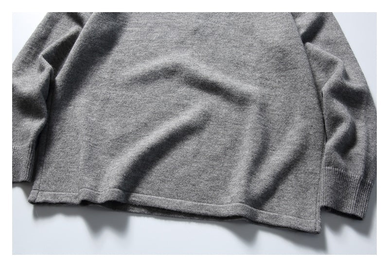 Close-up of a gray sweater laid flat, showing its lower hem and ribbed sleeve cuffs.