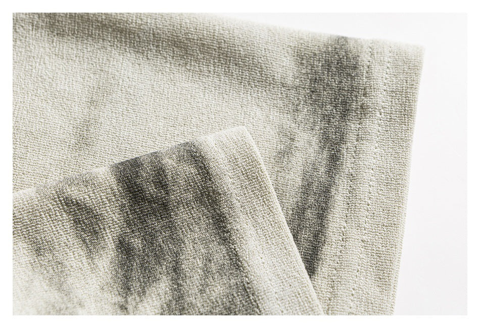 Close-up of folded ivory-gray shirt fabric with a dark mottled stripe pattern.