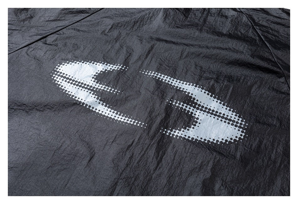 Close-up of black crinkled fabric with a large white dotted abstract graphic print.