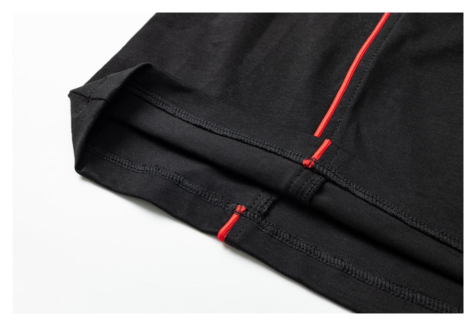 Close-up of the black shirt's finished hem, visible overlock stitching, and red piping.