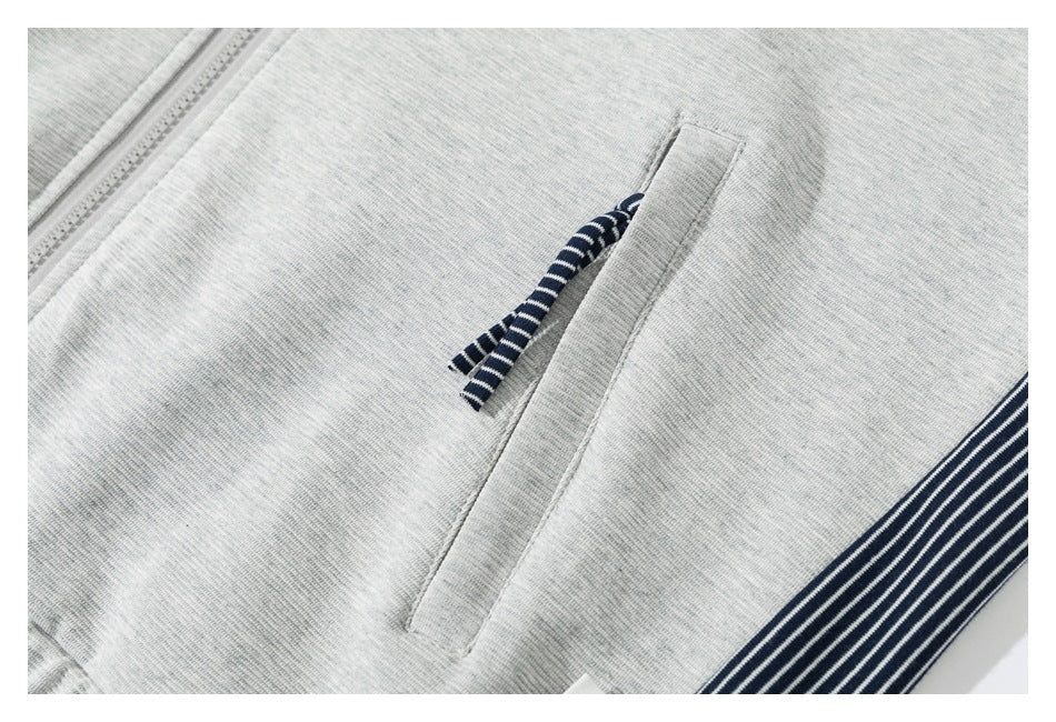 Close-up of light gray joggers with a zip pocket, navy-and-white striped pull, and striped side trim.