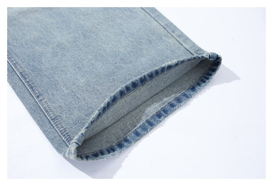 Close-up of a light blue washed jeans leg with the hem folded open to show the inside stitching.