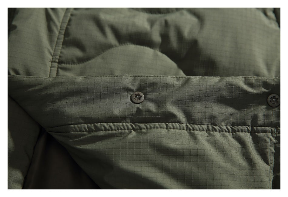 Close-up of two snap buttons on an olive jacket flap with a fine grid texture.