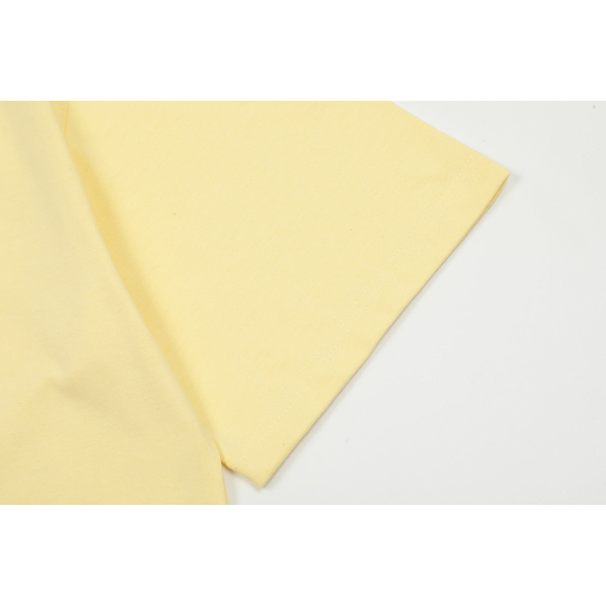 Close-up of the pale yellow T-shirt's short sleeve and stitched hem.
