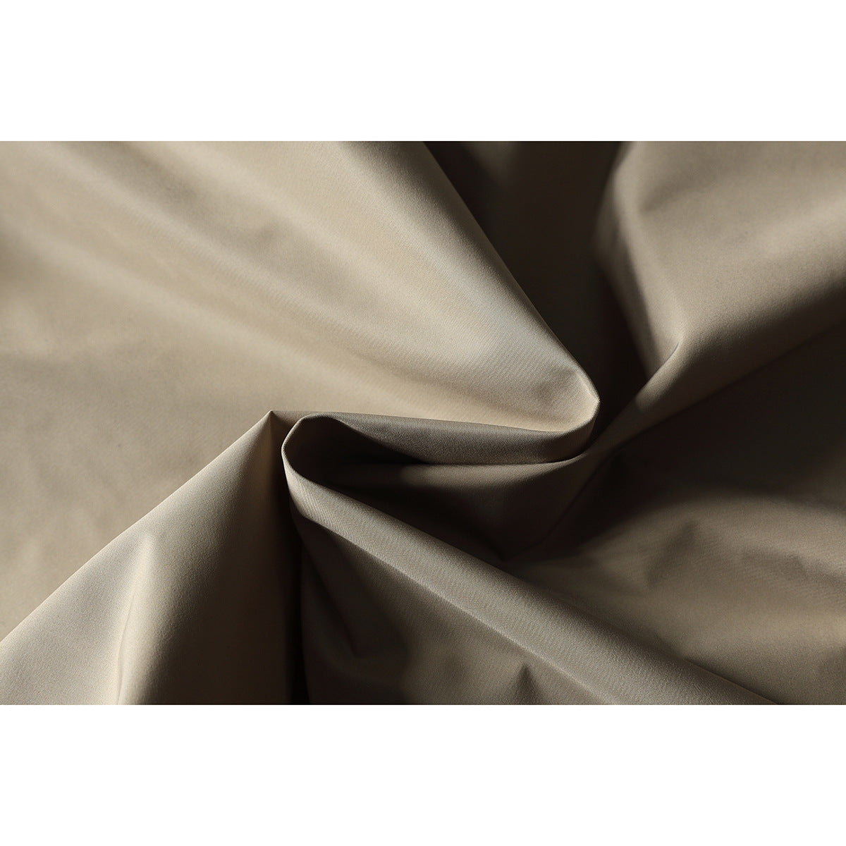 Close-up of smooth beige trouser fabric arranged in soft folds.