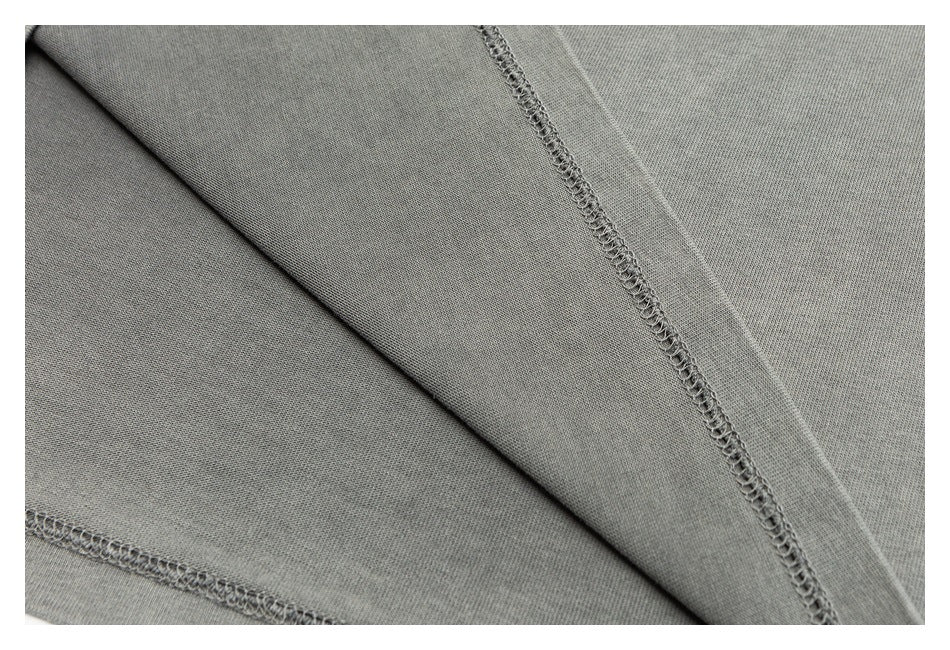 Close-up of gray garment fabric with visible overlock stitching along the seams.