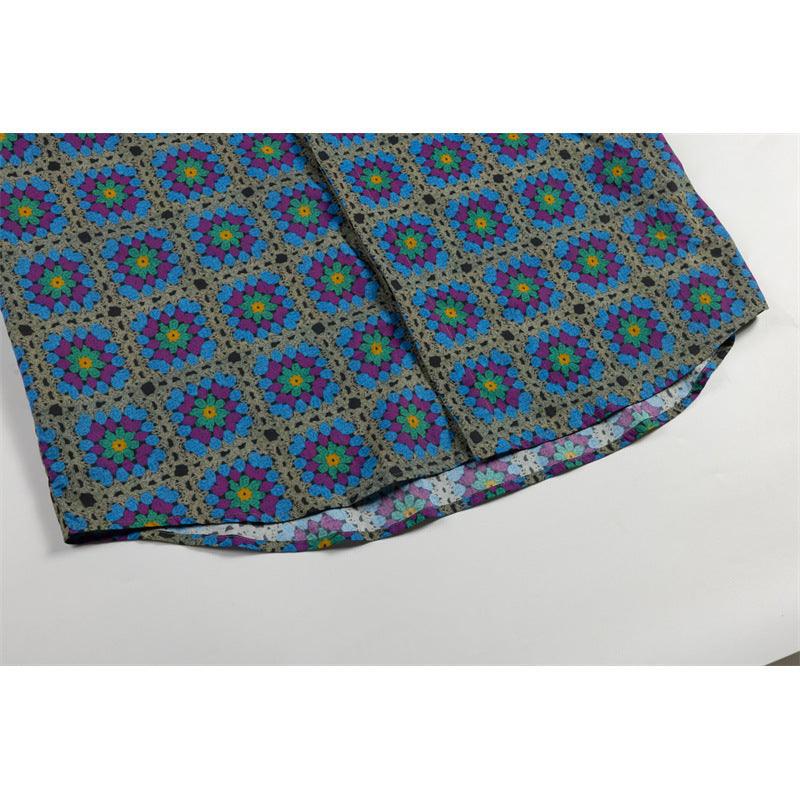 Close-up of the curved hem of a gray shirt with repeating blue, purple, and teal floral motifs.