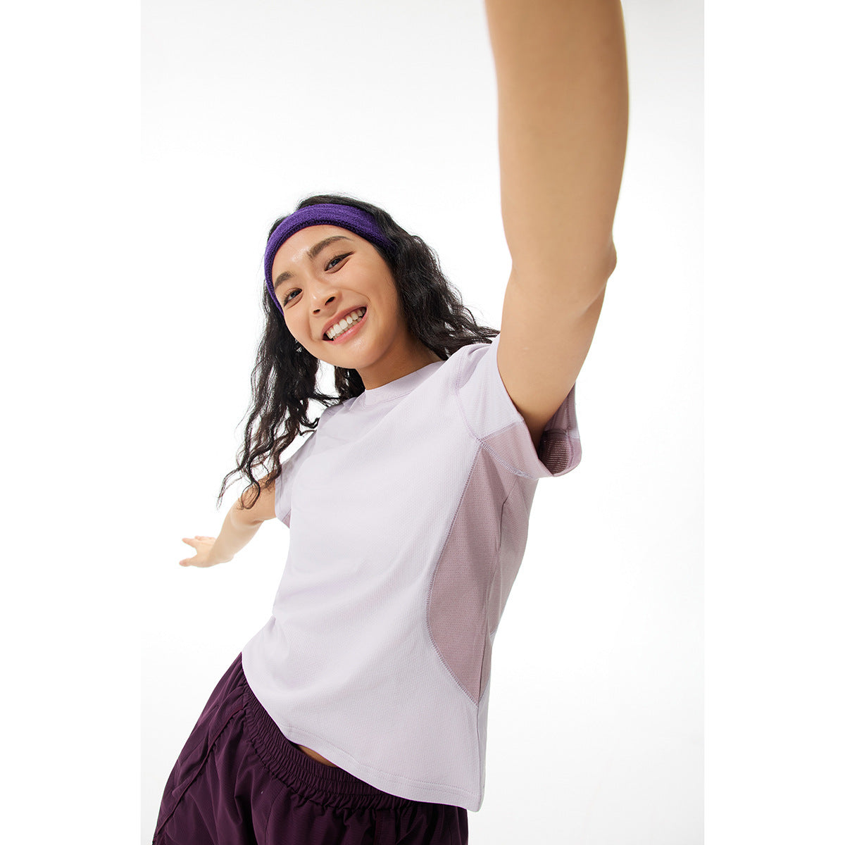 Close view of a model wearing a light lavender T-shirt with mauve side panels and dark plum shorts.
