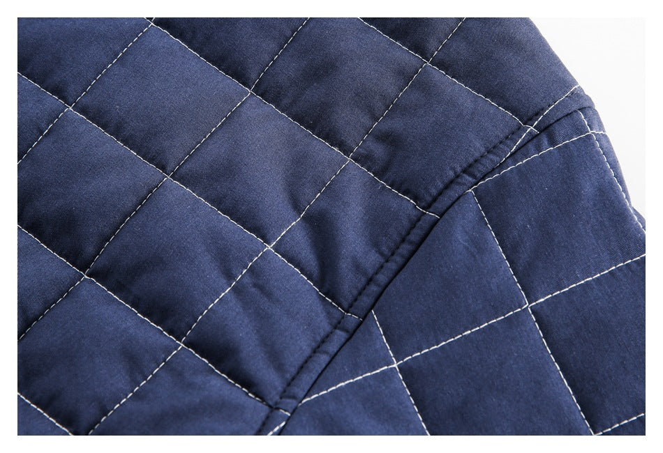 Close-up of navy quilted garment fabric with white stitching and a diagonal bound seam.