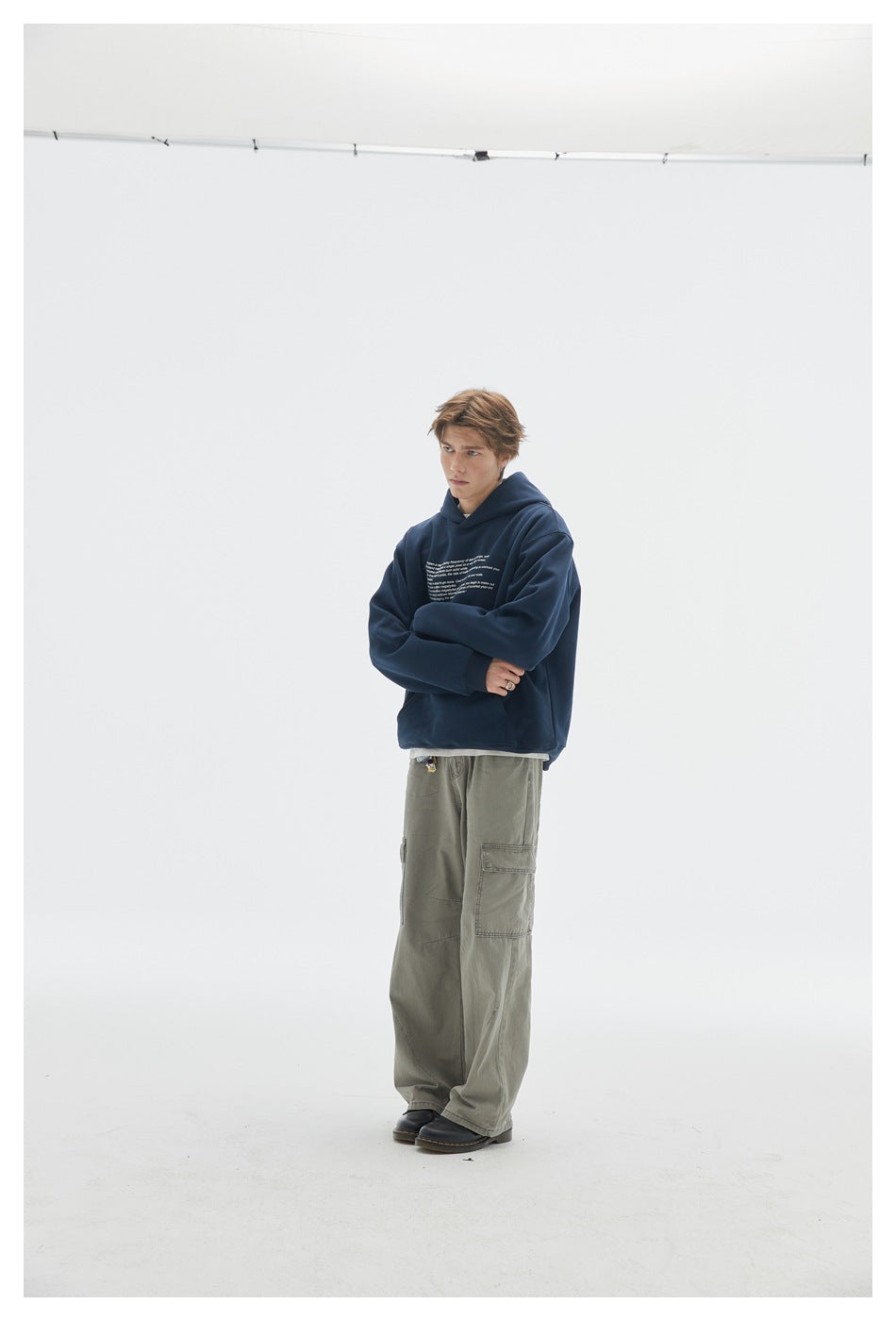 Model wearing a navy hoodie with small white chest text and olive cargo pants.