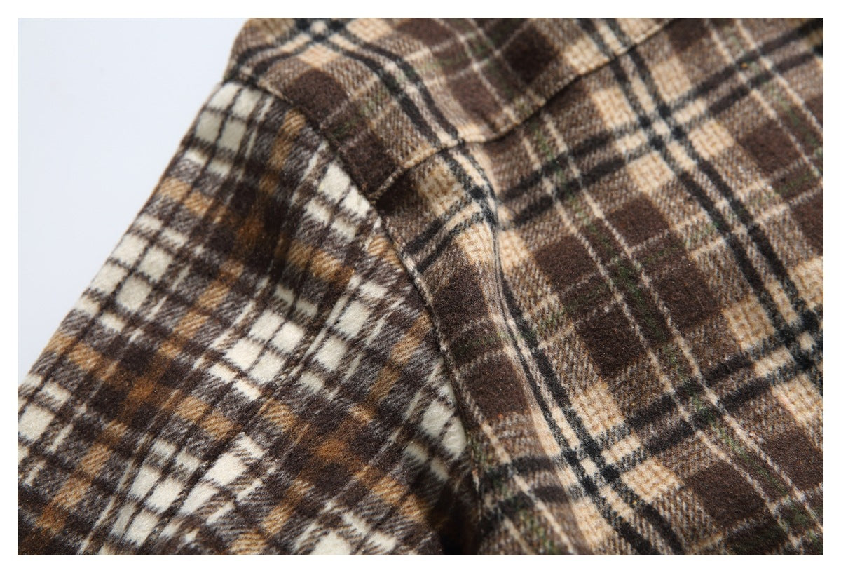 Close-up of the plaid shirt's shoulder and sleeve seam against a light background.