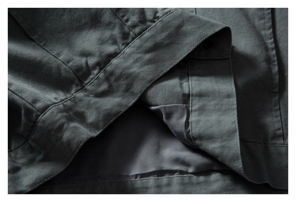 Close-up of a gray-green garment's inner lining, folded fabric, and a dark snap fastener.