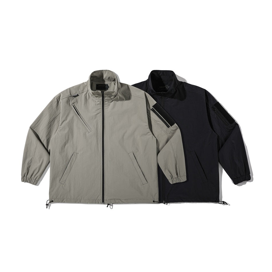 Two front-view jackets shown together: one light gray and one black, each with a zip front and angled chest pocket.