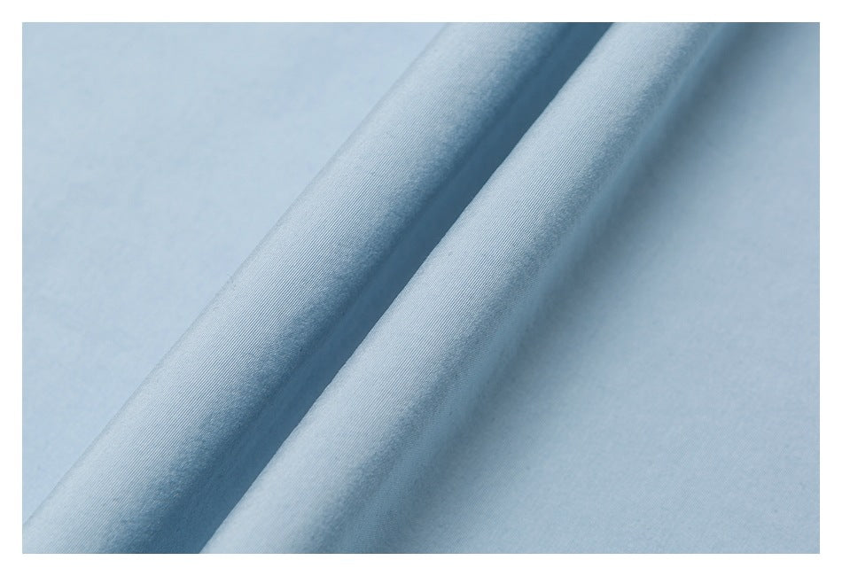 Close-up of light blue fabric folded into soft diagonal ridges.