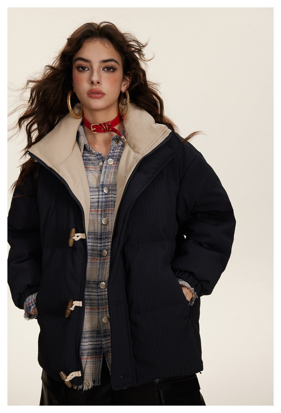 Model wearing an open dark padded jacket with beige lining, toggle closures and a wide collar.
