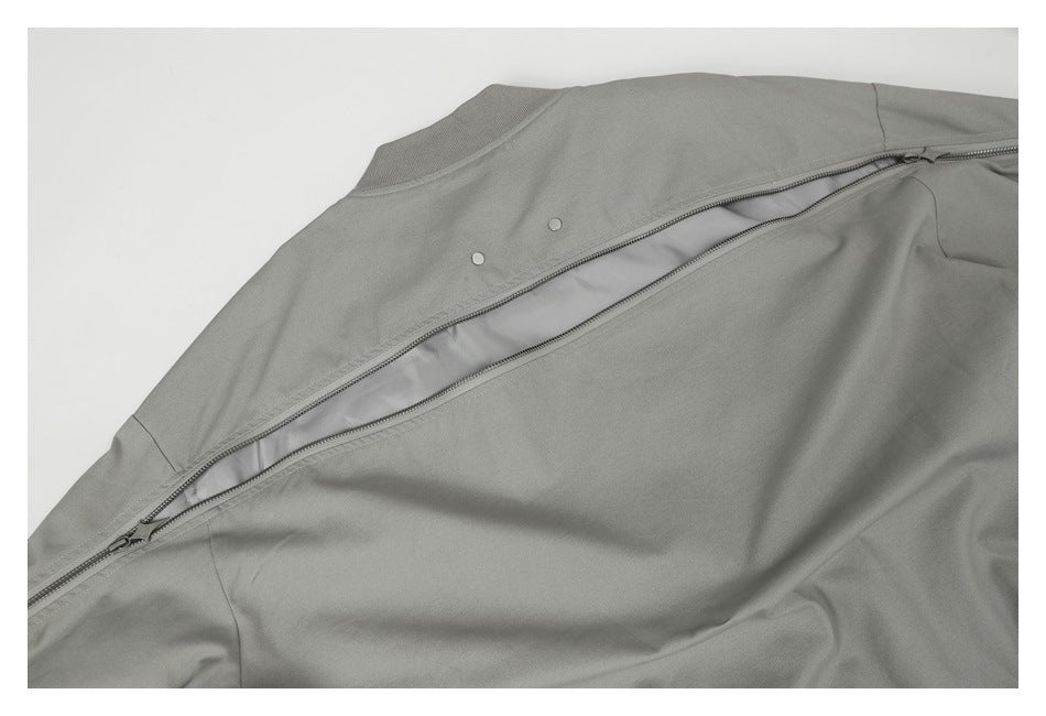 Close-up of a gray garment with a long diagonal zipper and two small snaps.