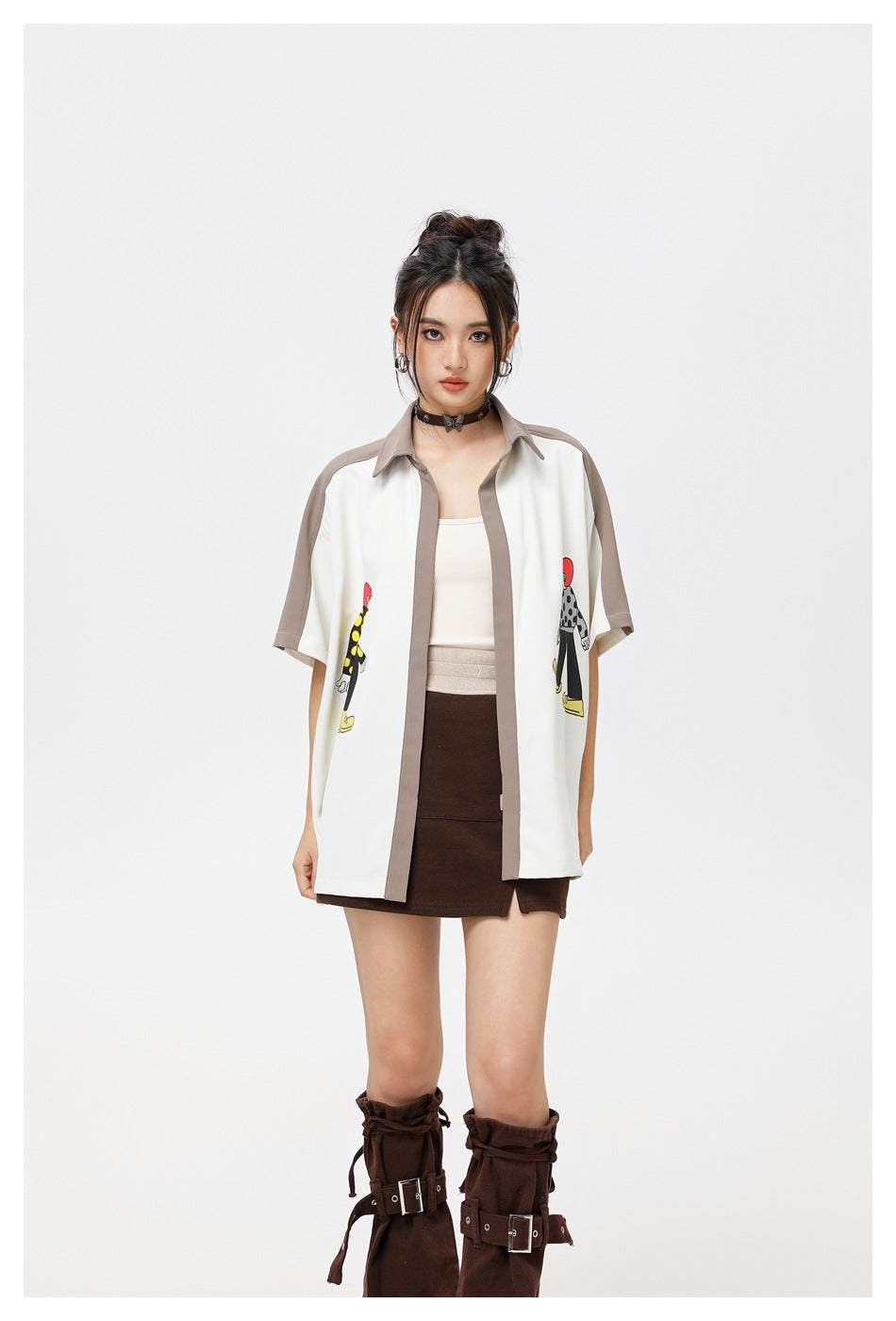 Model wearing the color-block short-sleeve shirt open over a cream tank top with a brown mini skirt