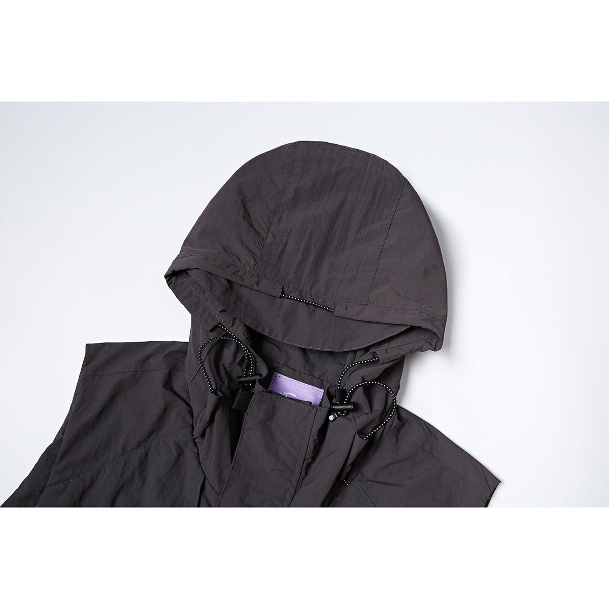 Close-up of a dark hooded vest showing the hood, drawcords, and front closure.