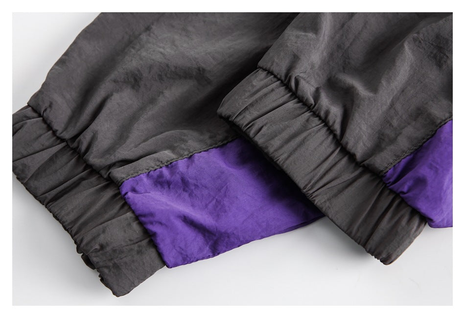 Close-up of a charcoal and purple color-block jacket hem with gathered elastic edges.