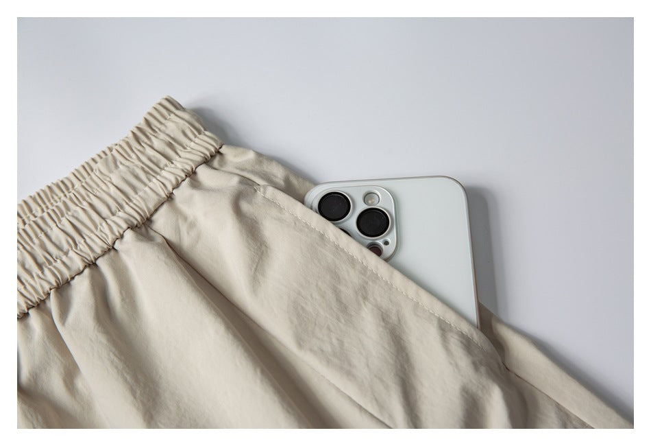 Close-up showing a smartphone tucked into the side pocket of the light beige shorts.