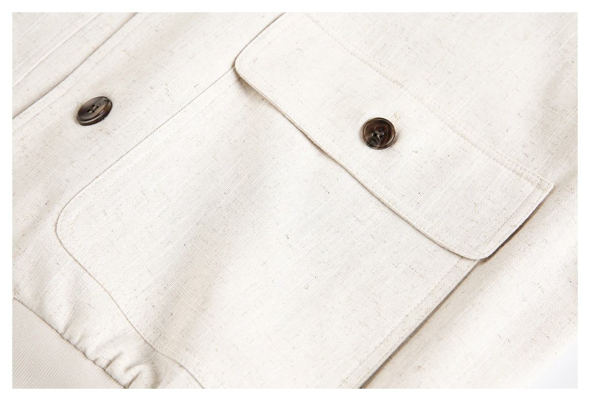 Close-up of a cream jacket flap pocket, dark button, and stitched seams.