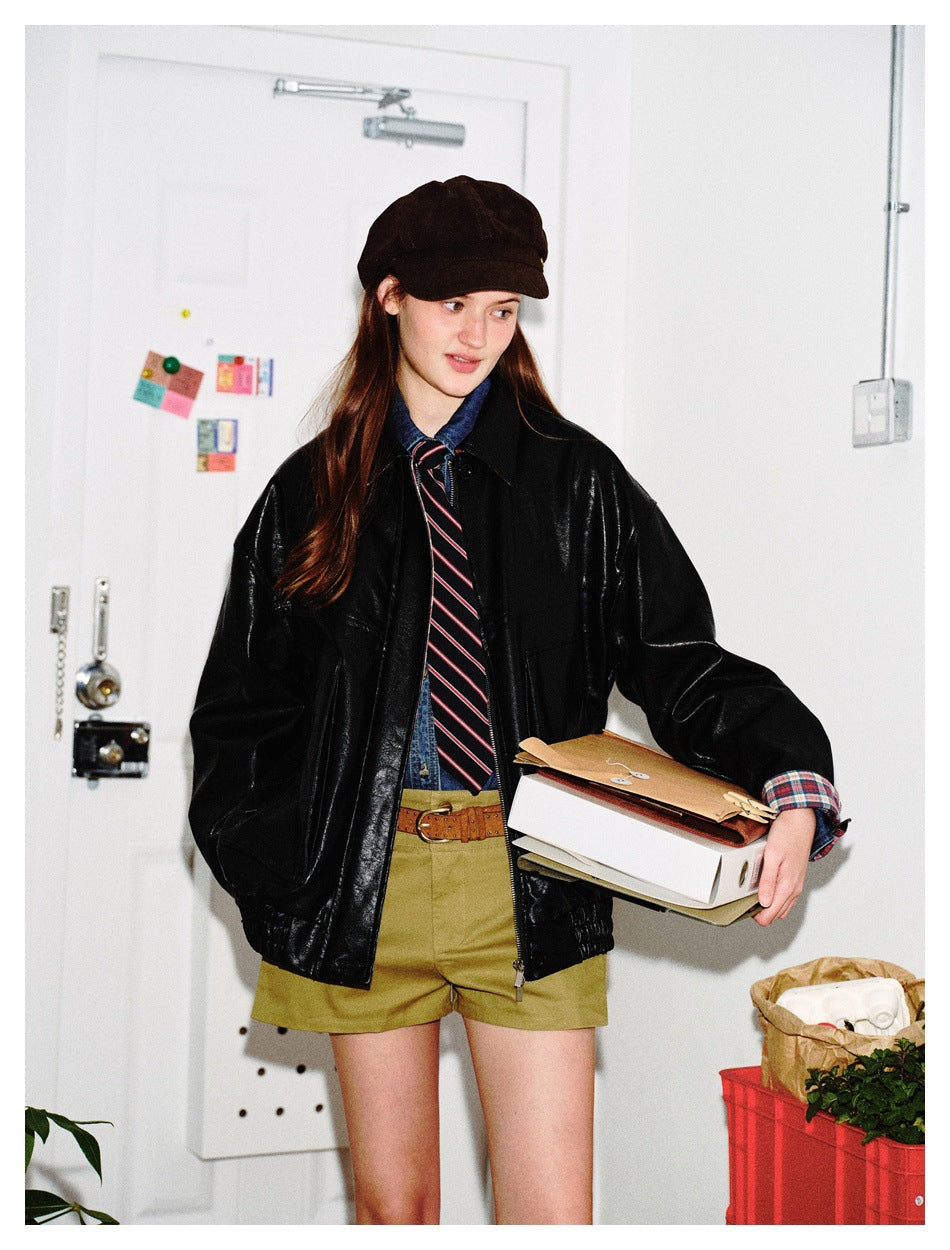 Model wearing the black faux-leather jacket open over a denim shirt, striped tie and olive shorts