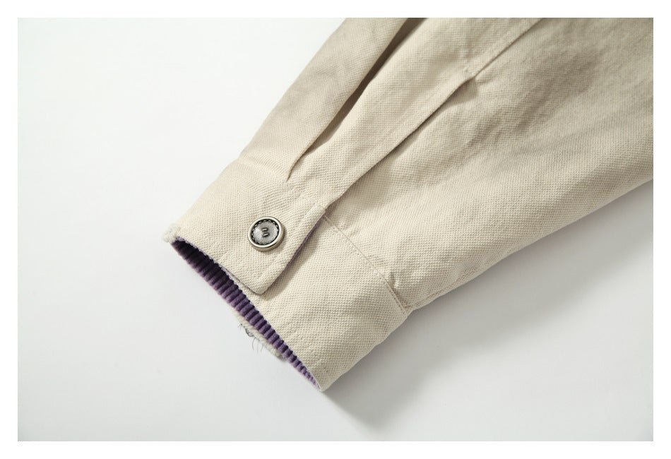 Close-up of a beige sleeve cuff with a metal button and purple ribbed lining.