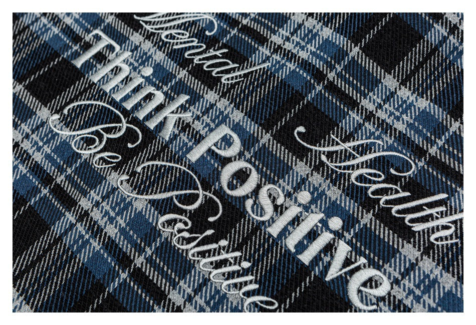 Blue, black, and gray plaid fabric with white embroidered English lettering and decorative flourishes.