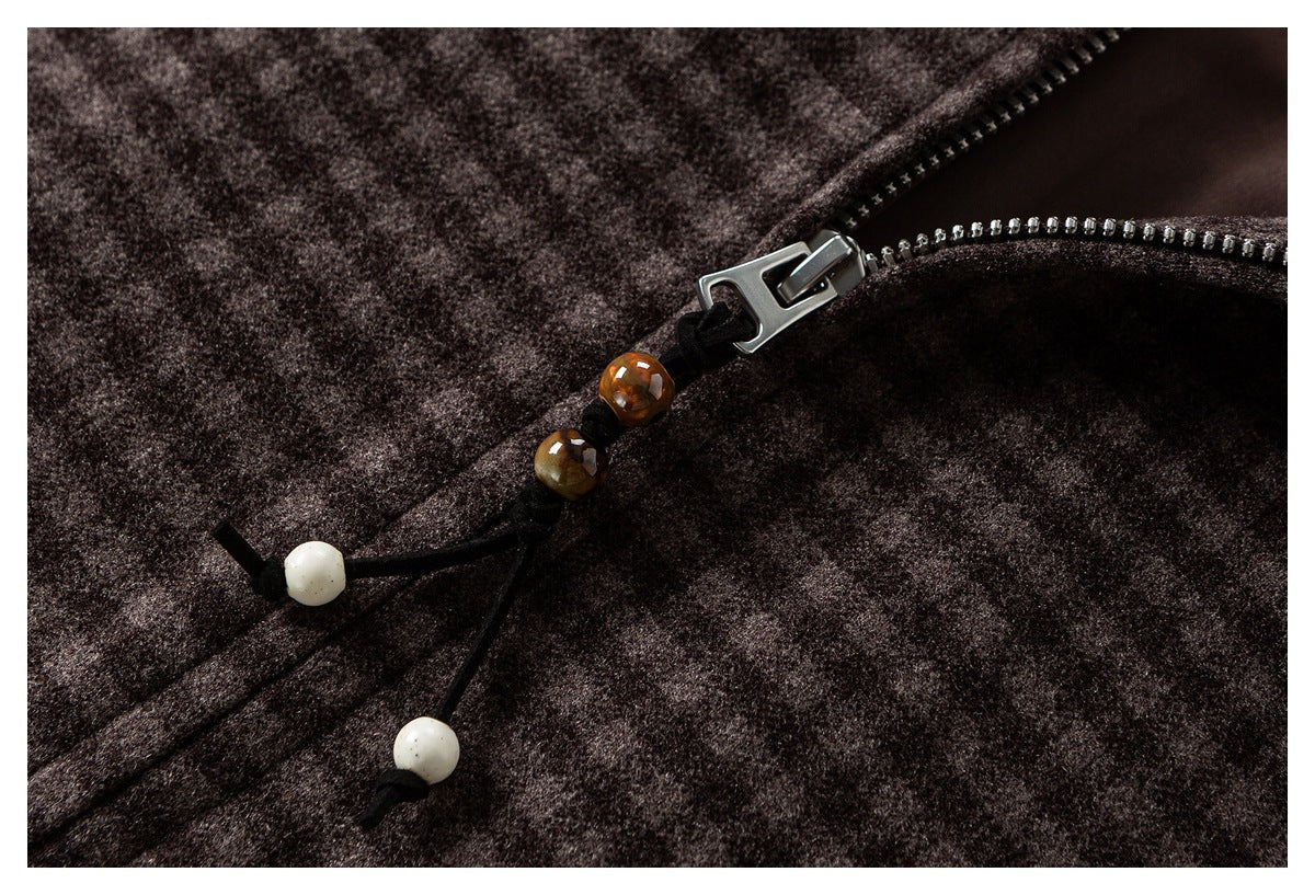 Close-up of a silver zipper with a beaded pull on dark brown mottled fabric.