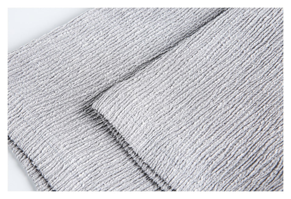 Close-up of light gray textured fabric with a folded edge and visible stitching.
