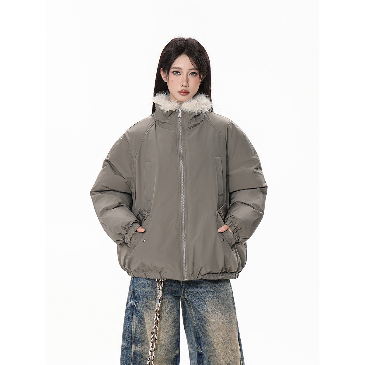 Front view of a model wearing a taupe-gray jacket with a cream fur-trimmed collar, zip closure and pockets.