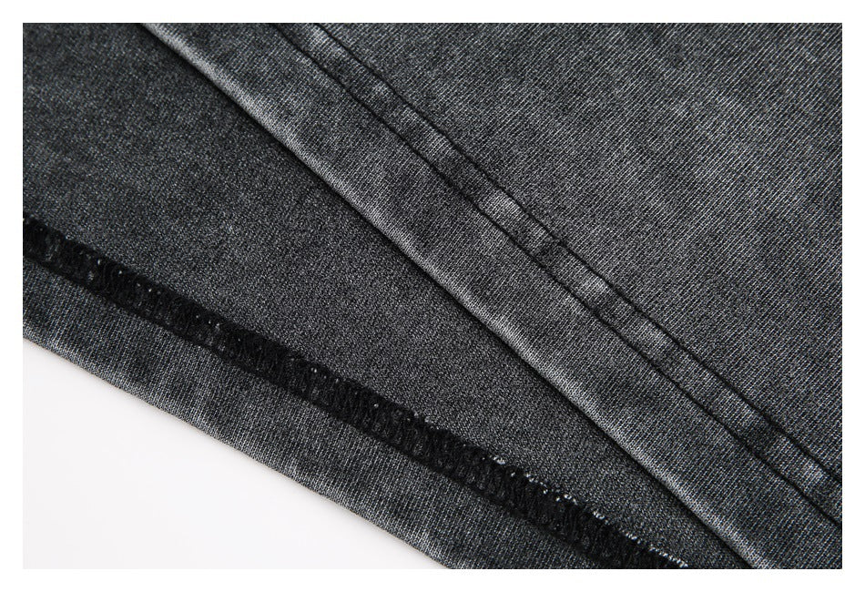 Close-up of charcoal garment fabric showing a folded seam and black overlock stitching.