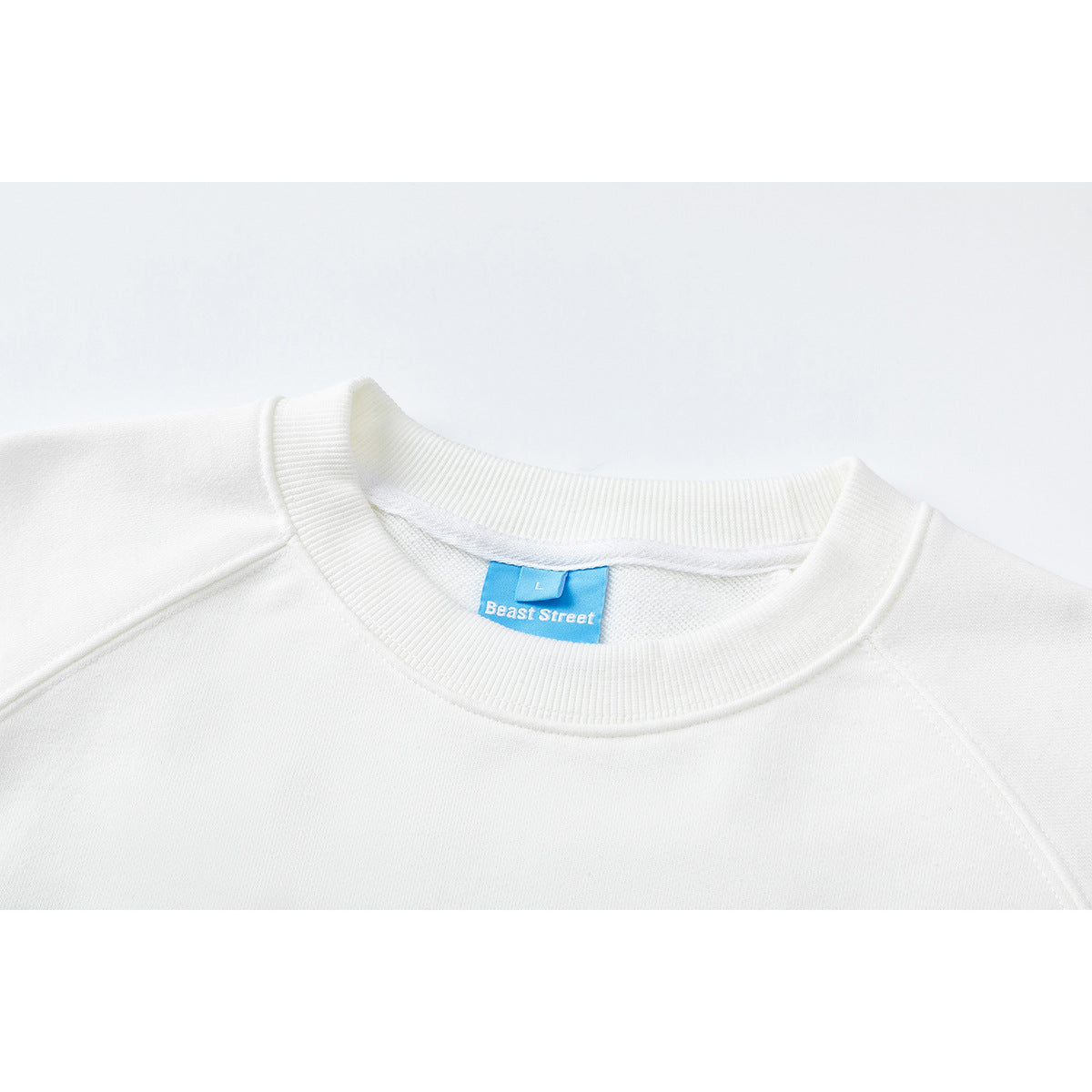 Close-up of the ribbed neckline and blue brand label on a white sweatshirt.