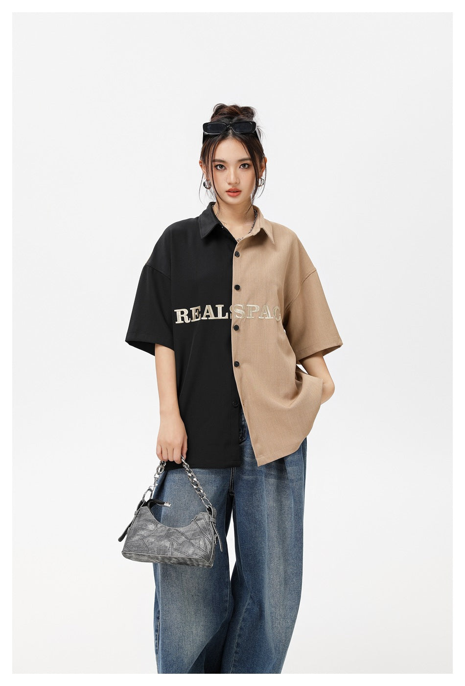 Model wearing black and khaki color-block short-sleeve shirt with embroidered lettering, wide-leg jeans and a gray shoulder