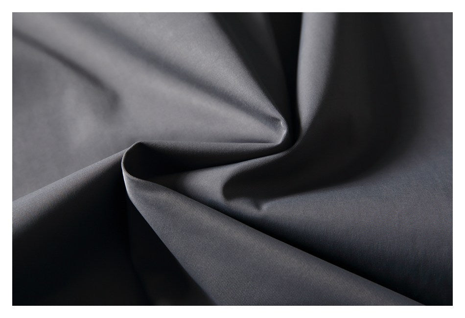Close-up of smooth charcoal-gray fabric draped into soft folds.