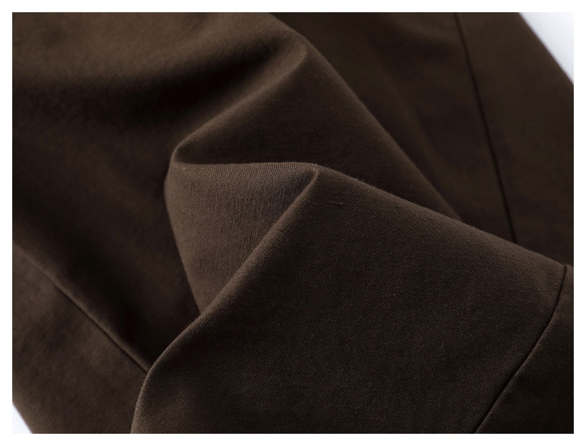 Close-up of dark brown fabric showing its fine weave and draped folds.
